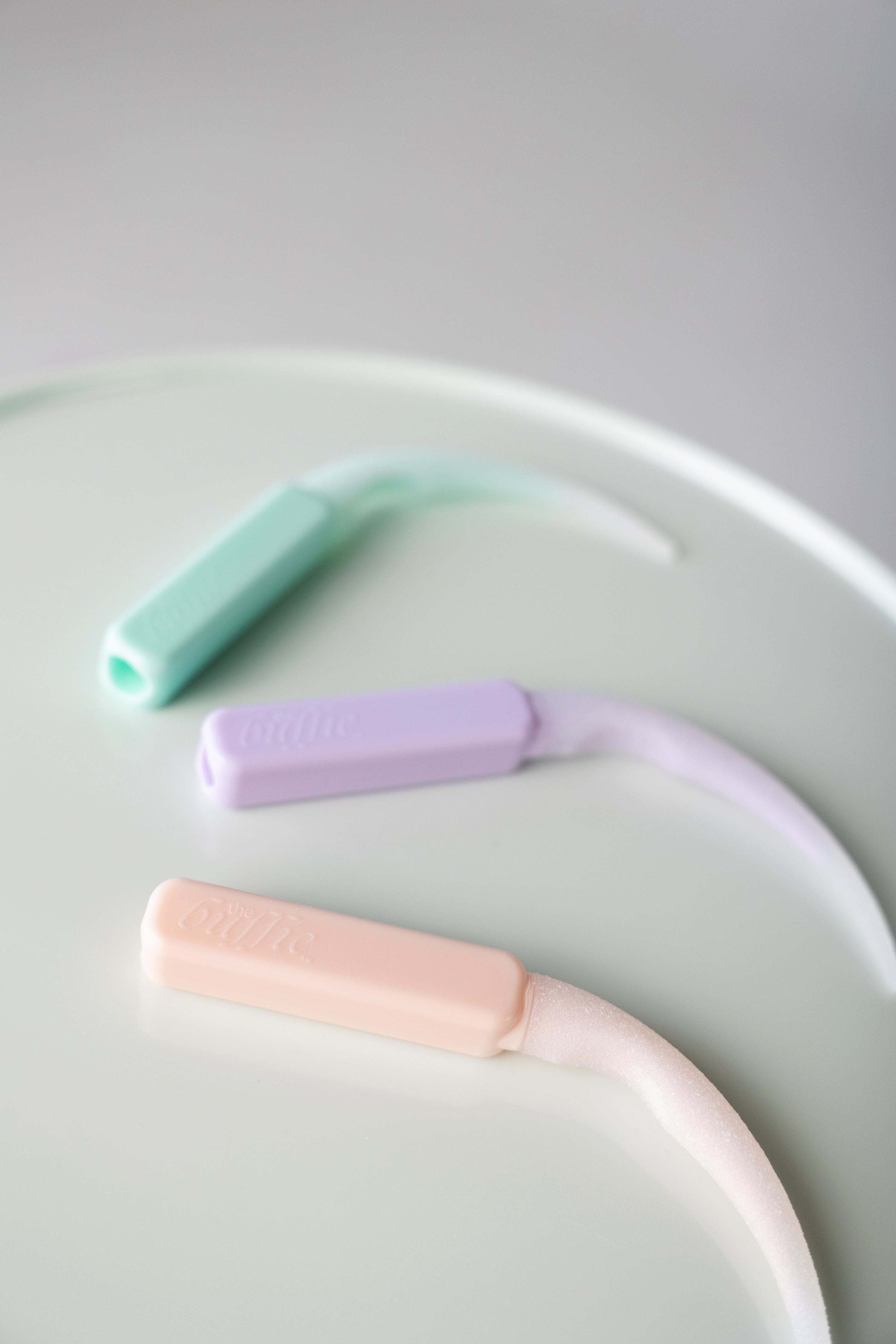 Three pastel-colored buffies on a pastel green surface.