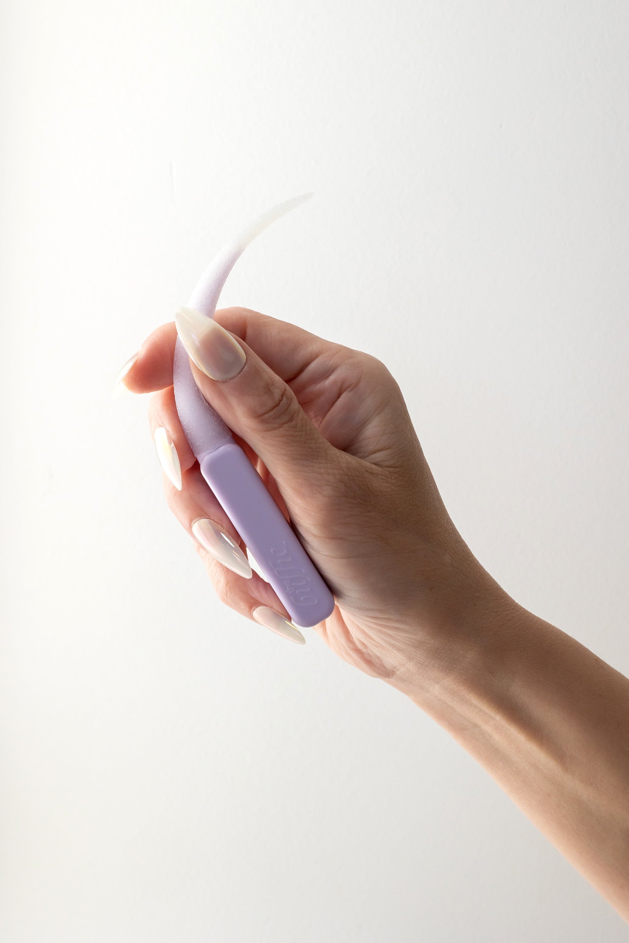 Hand holding a light purple buffie with a hand that has white press ons against a white background