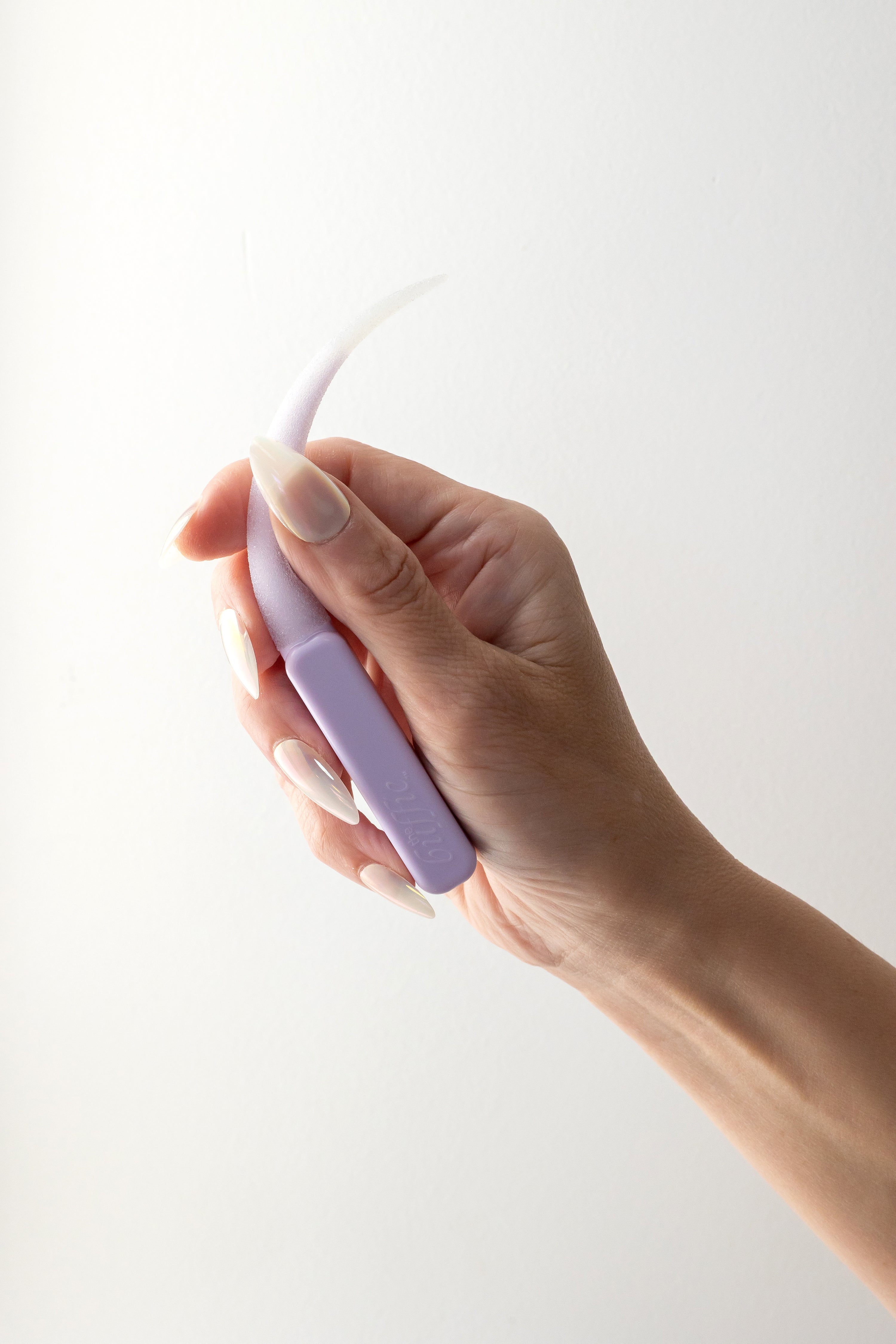 Hand holding a light purple buffie with a hand that has white press ons against a white background