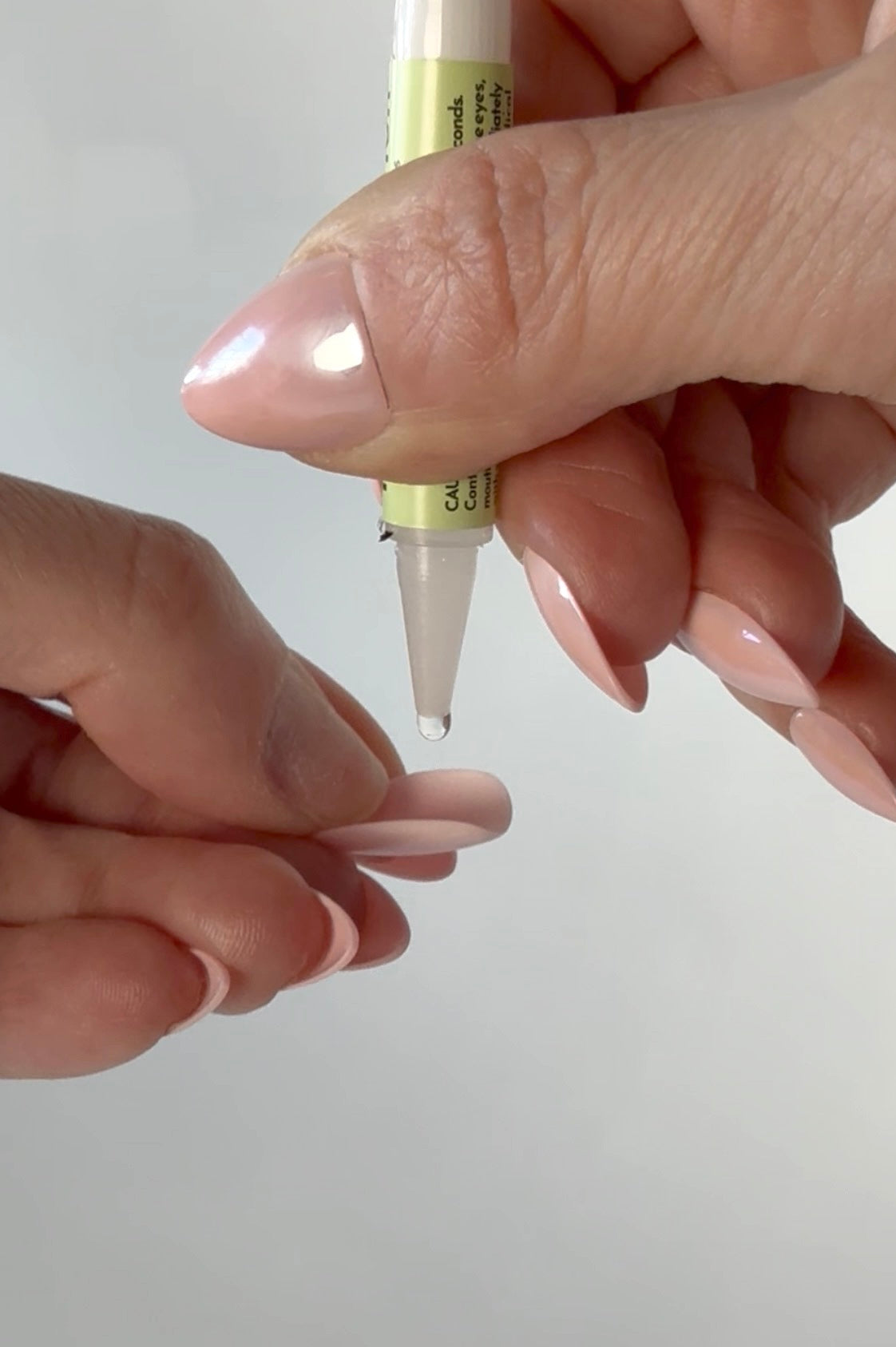 Person applying a clear nail glue to back of press on nail